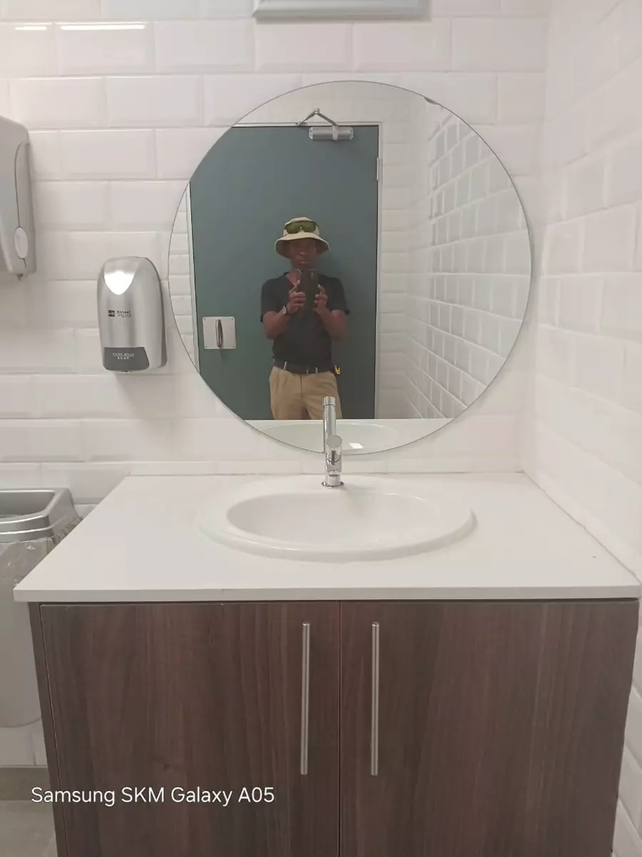 Bathroom vanity with a round mirror and tiled walls