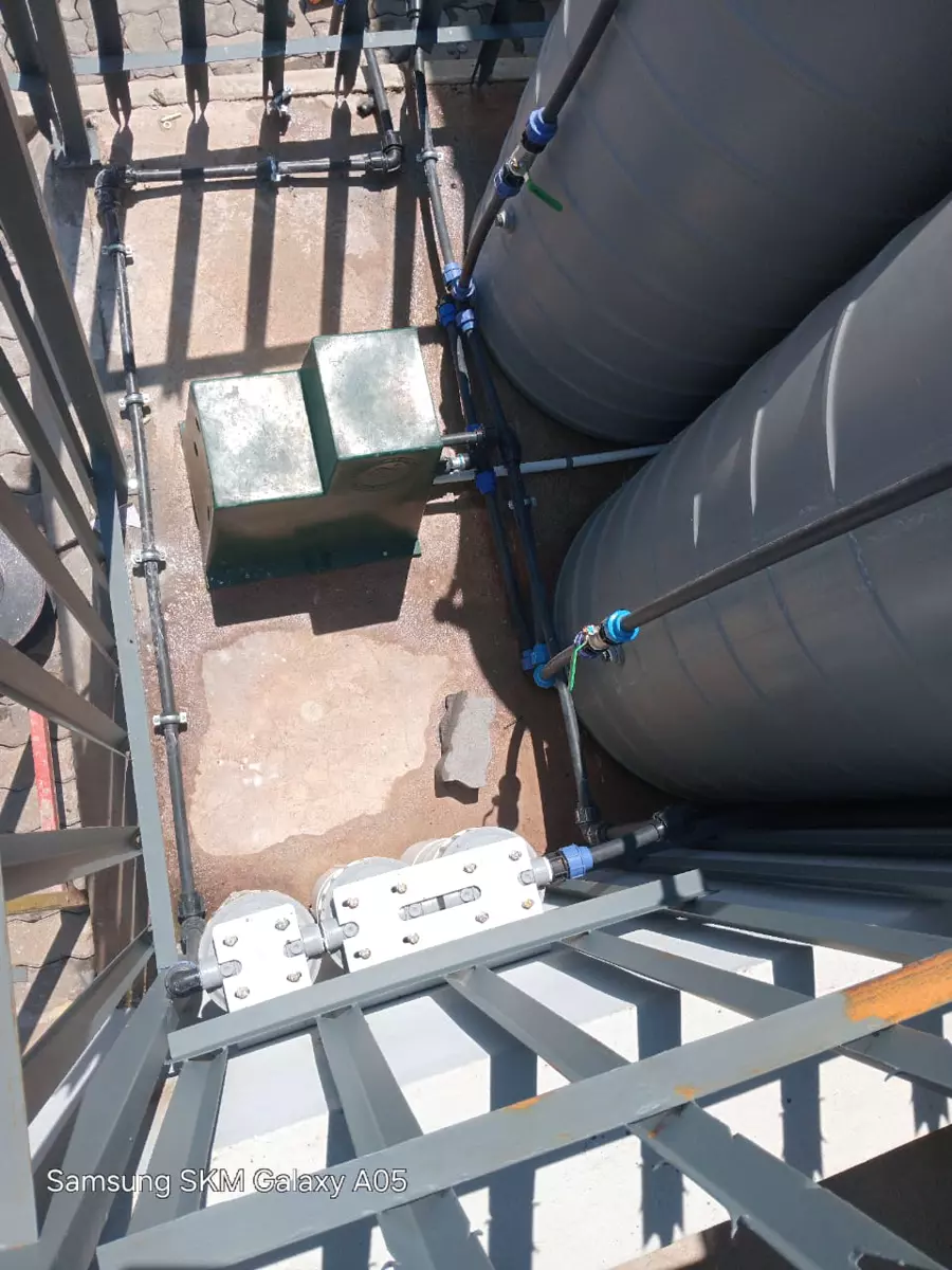 Water tanks and pump plumbing installation enclosed by a metal security gate